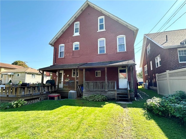 back of property with brick siding, fence, central AC, covered porch, and a lawn