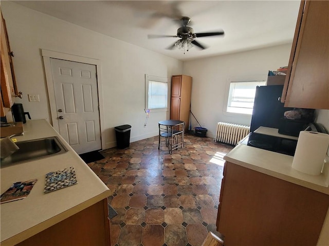 kitchen featuring light countertops, radiator, a wealth of natural light, and a sink