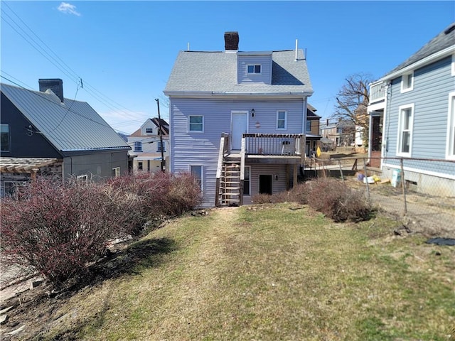 rear view of house with stairway, fence, a chimney, a deck, and a lawn