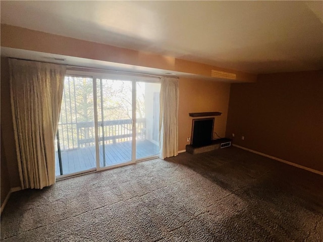 unfurnished living room with visible vents, a fireplace with raised hearth, baseboards, and carpet floors