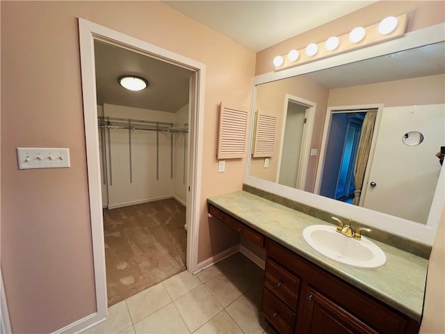 bathroom featuring tile patterned flooring, a spacious closet, vanity, and baseboards