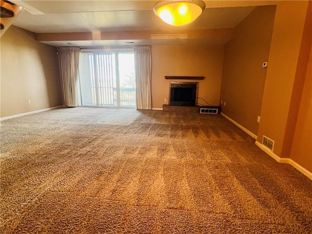 unfurnished living room featuring visible vents, a fireplace with raised hearth, baseboards, and carpet