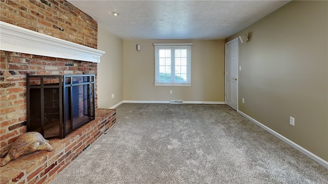 unfurnished living room with a brick fireplace, carpet, baseboards, and a textured ceiling