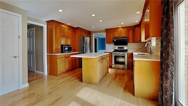 kitchen with a sink, light wood finished floors, appliances with stainless steel finishes, and light countertops