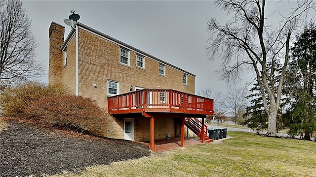 back of house with a lawn, a chimney, a wooden deck, brick siding, and stairs