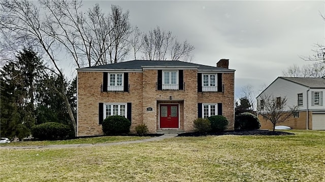 colonial home featuring a front yard, brick siding, and a chimney