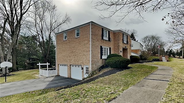 view of home's exterior featuring a yard, brick siding, a garage, and driveway