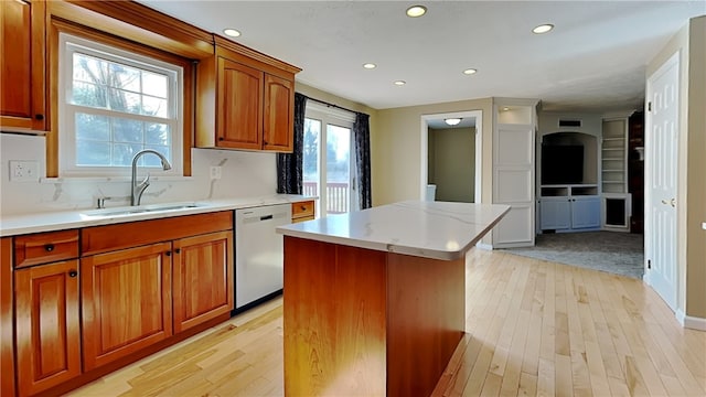 kitchen with a wealth of natural light, dishwashing machine, a kitchen island, and a sink