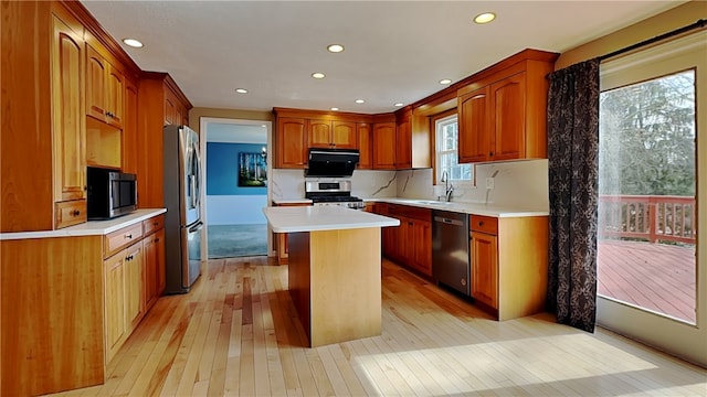 kitchen featuring light wood finished floors, a sink, stainless steel appliances, light countertops, and a center island