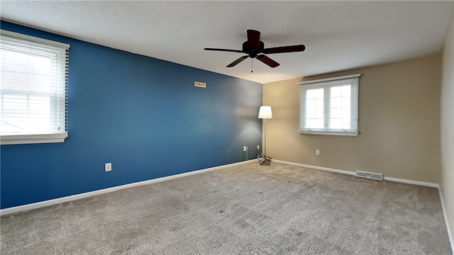 empty room featuring a ceiling fan, visible vents, carpet, and baseboards