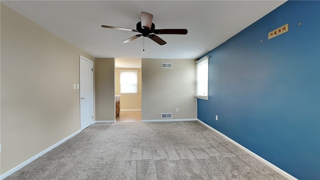 empty room with visible vents, plenty of natural light, and light colored carpet