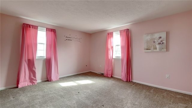 spare room featuring visible vents, baseboards, a textured ceiling, and carpet