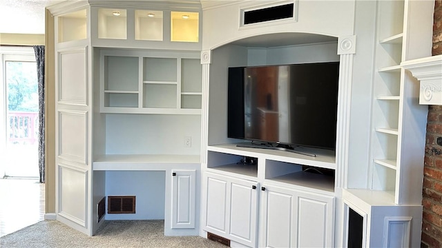 unfurnished living room with visible vents, built in shelves, and light colored carpet