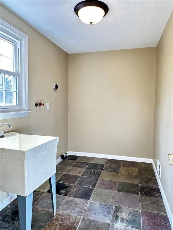 clothes washing area with stone tile floors, visible vents, and baseboards