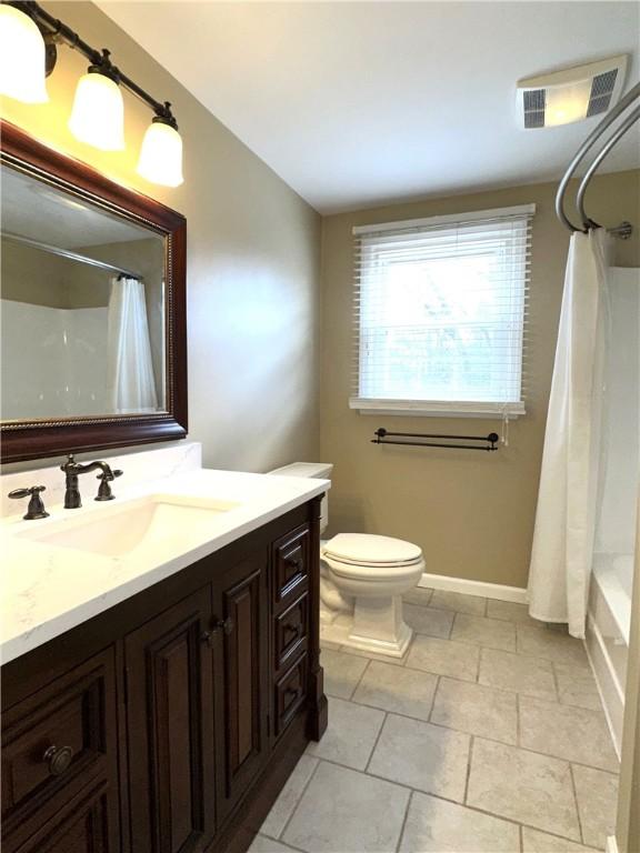 full bathroom featuring visible vents, toilet, shower / bath combination with curtain, baseboards, and vanity