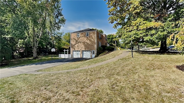 view of side of property with a yard, an attached garage, and aphalt driveway