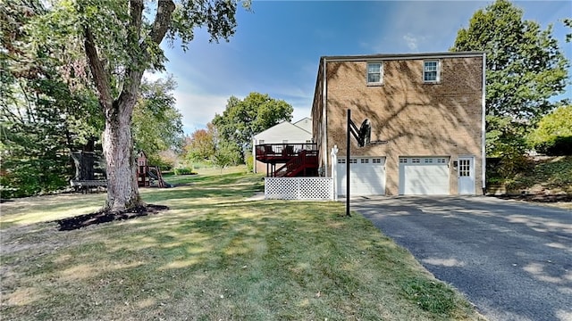 view of side of home with a garage, a wooden deck, a playground, a lawn, and driveway