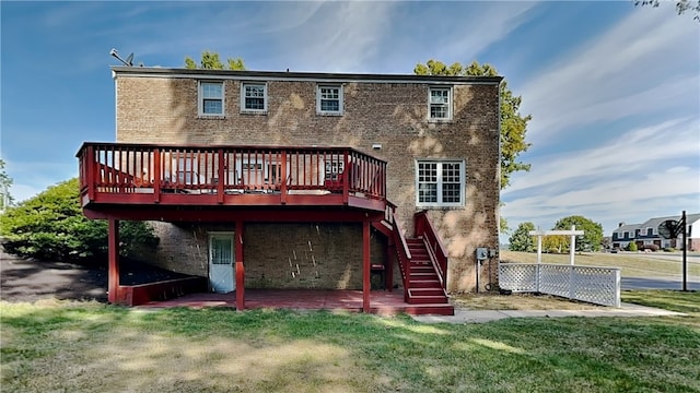 rear view of property with a yard, brick siding, a patio area, and a deck