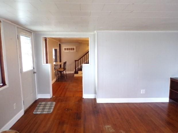 interior space with visible vents, stairway, wood finished floors, and baseboards