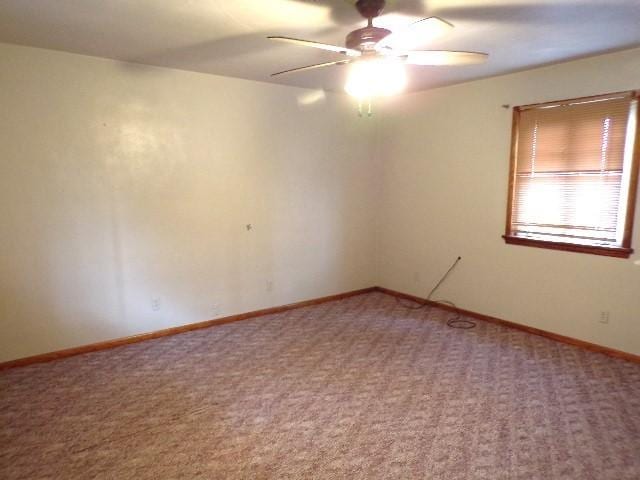 carpeted spare room with ceiling fan and baseboards