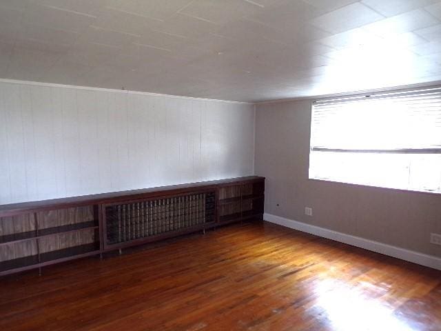 spare room with baseboards and wood finished floors