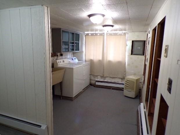 clothes washing area with a baseboard heating unit, electric panel, laundry area, washer and dryer, and a baseboard radiator