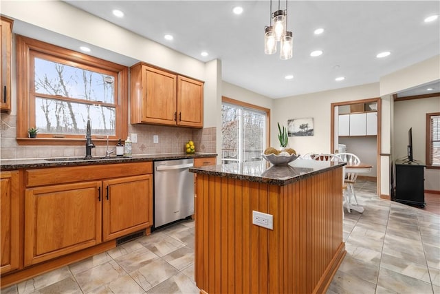 kitchen featuring a sink, dark stone countertops, a kitchen island, stainless steel dishwasher, and decorative backsplash