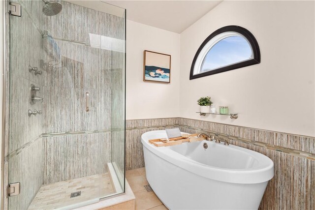 full bath featuring wainscoting, a stall shower, a freestanding tub, tile patterned floors, and tile walls