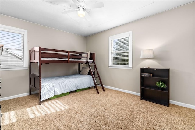 carpeted bedroom featuring baseboards, multiple windows, and a ceiling fan