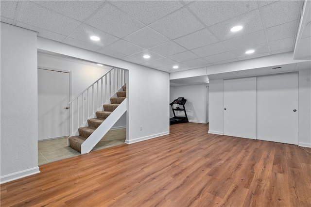 finished below grade area with recessed lighting, baseboards, wood finished floors, and stairs