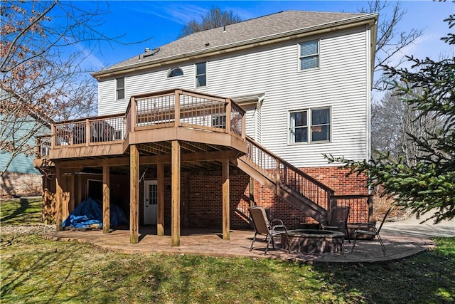 back of property featuring brick siding, a fire pit, stairway, a wooden deck, and a patio area