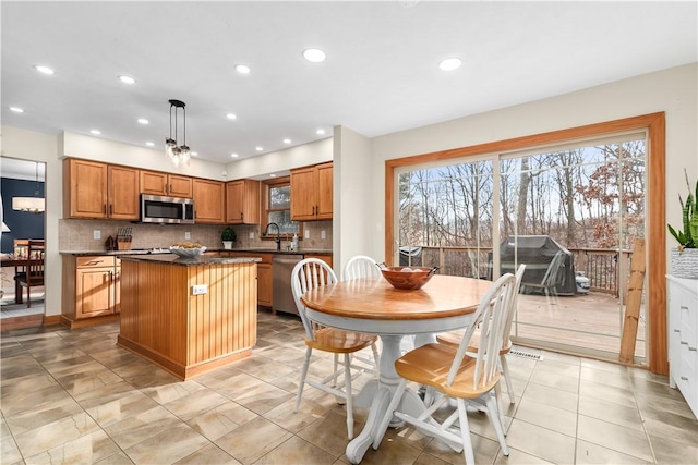 kitchen featuring brown cabinets, a kitchen island, dark countertops, tasteful backsplash, and stainless steel appliances