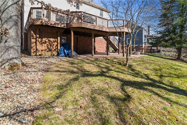 back of house featuring brick siding, stairway, a wooden deck, a yard, and a patio