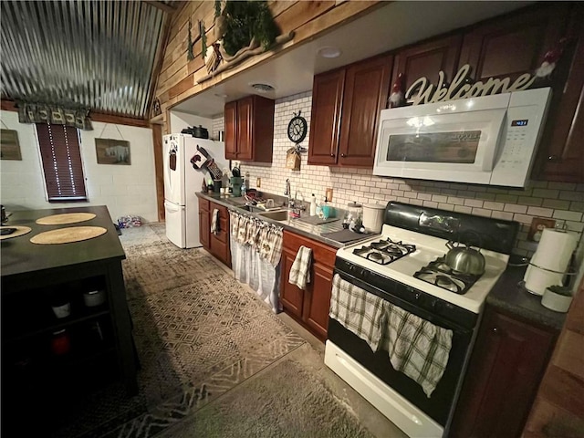 kitchen featuring white appliances, dark countertops, backsplash, and a sink