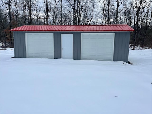 snow covered garage featuring a detached garage