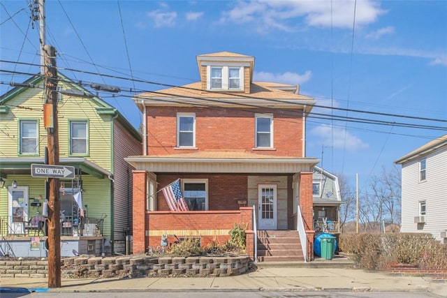 american foursquare style home featuring a porch and brick siding