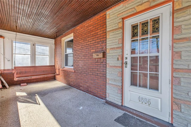 view of exterior entry featuring brick siding and a porch