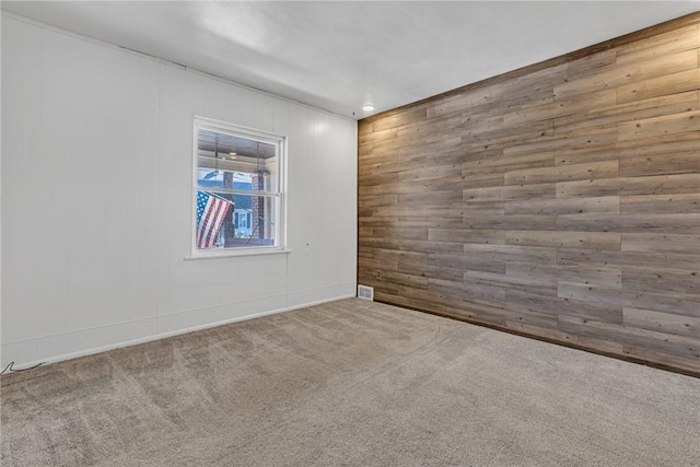 carpeted empty room with wooden walls and visible vents