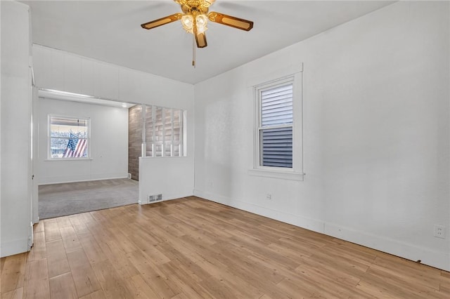 spare room with visible vents, a ceiling fan, light wood-type flooring, and baseboards