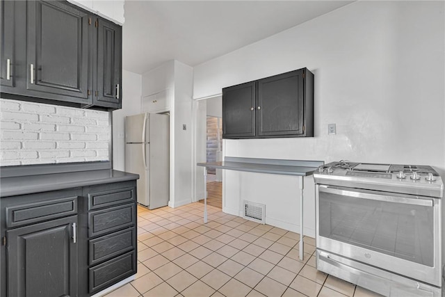 kitchen featuring gas stove, visible vents, light tile patterned floors, and freestanding refrigerator