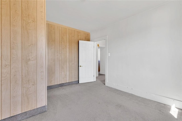 unfurnished room featuring wood walls and carpet flooring