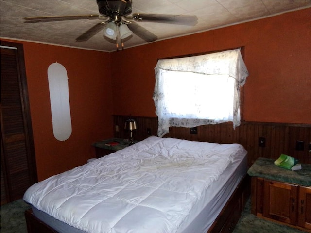 bedroom with a wainscoted wall and ceiling fan