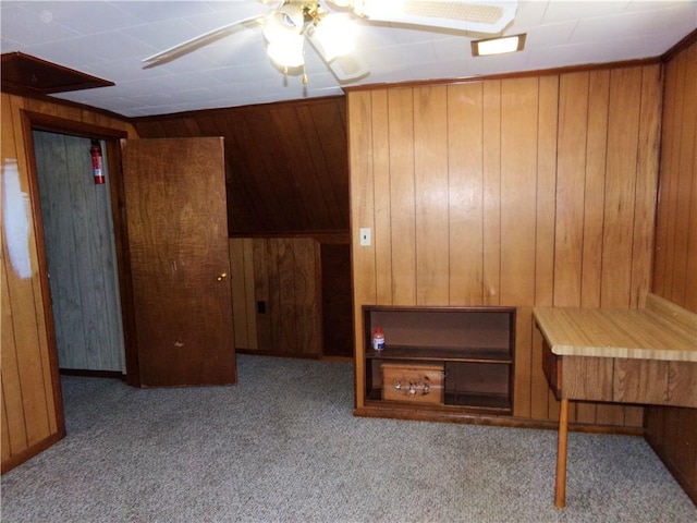 interior space with wood walls, carpet floors, and ceiling fan