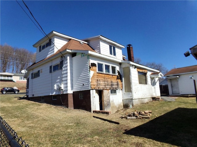 back of house featuring a chimney and a yard