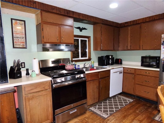 kitchen with black microwave, under cabinet range hood, stainless steel range with gas stovetop, dishwasher, and a sink