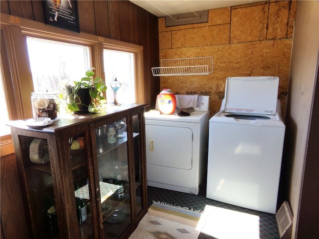 laundry room with laundry area, independent washer and dryer, visible vents, and wood walls