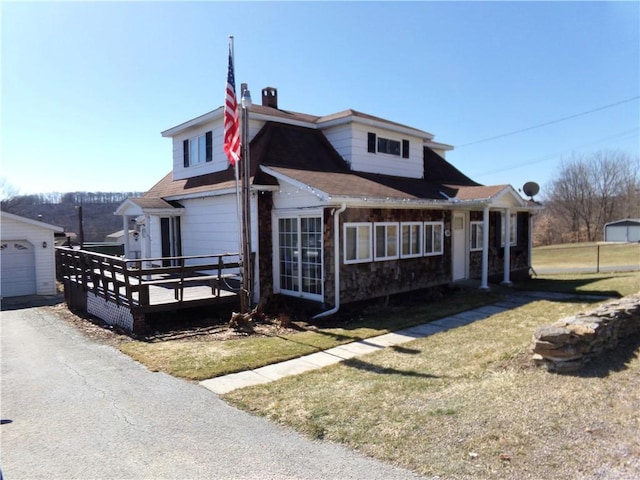 view of front of property featuring a wooden deck, a garage, a front yard, and a shingled roof