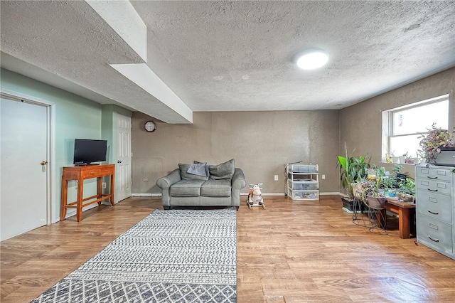 living area featuring baseboards, light wood-type flooring, and a textured ceiling