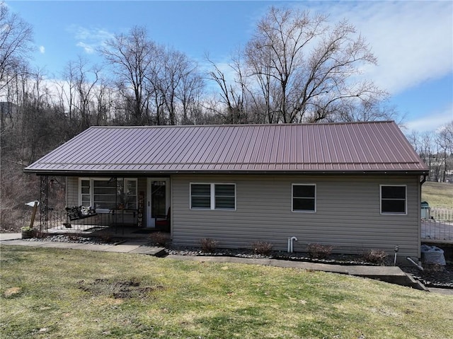 back of property featuring covered porch, metal roof, and a yard