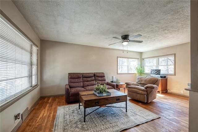 living room with visible vents, baseboards, ceiling fan, wood finished floors, and a textured ceiling